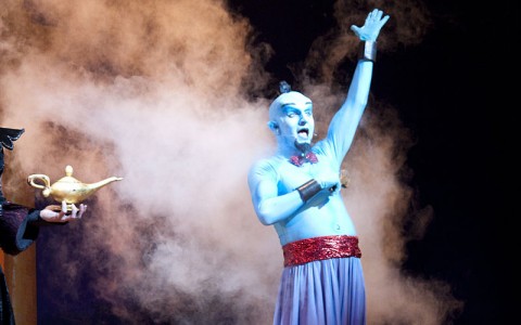 Genie from Aladdin on stage surrounded by smoke